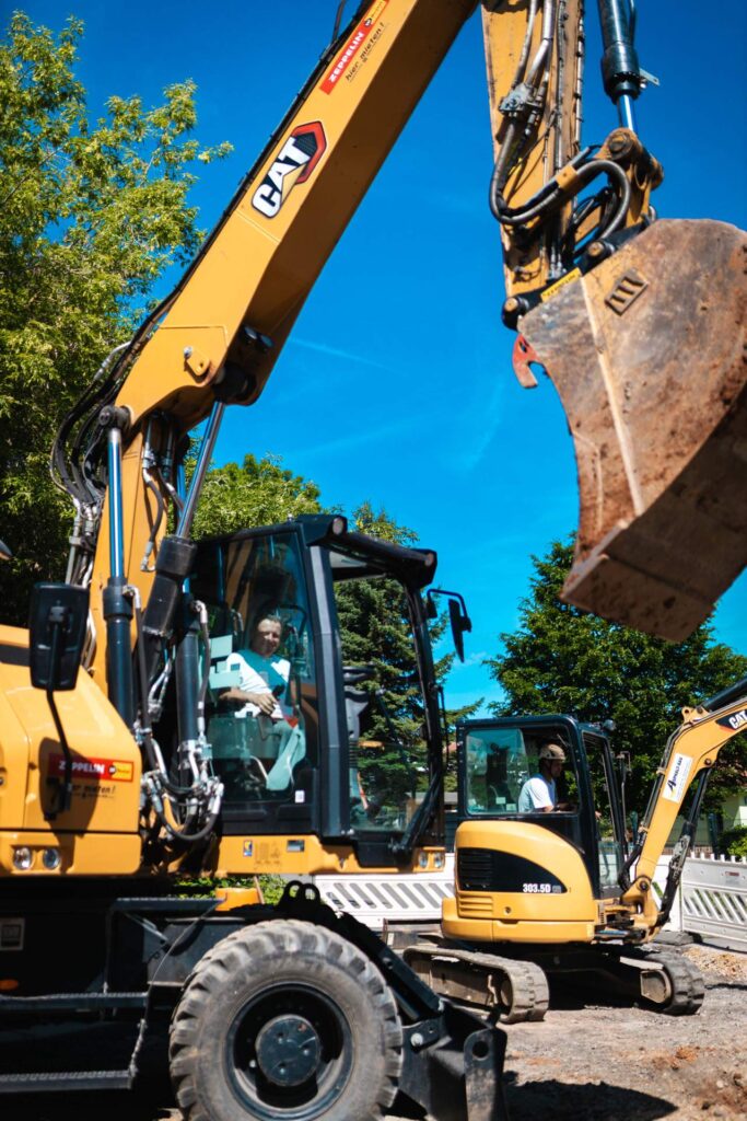 Gelber CAT-Mobilbagger auf der Straßenbaustelle beim Einsatz für Erdarbeiten.