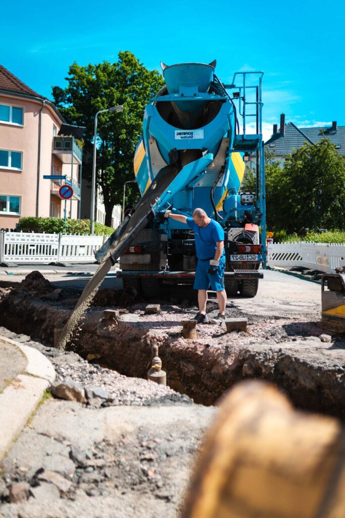 Betonmischer befüllt eine Baugrube über eine Förderrutsche beim Leitungsbau.
