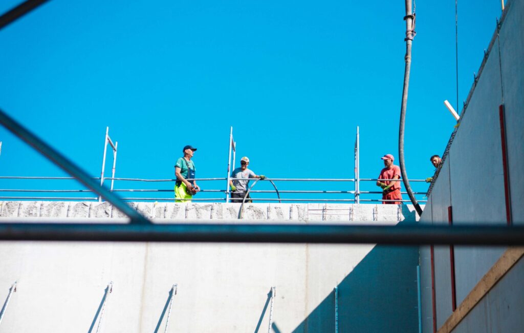 Bauarbeiter bei Betonierungsarbeiten an einer hohen Betonwand auf der Baustelle