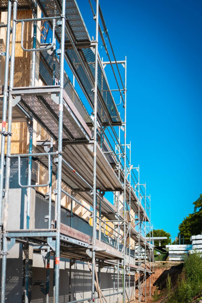 Perspektive von unten auf mehrstöckiges Fassadengerüst vor Holzbau-Elementen