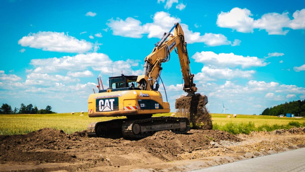 CAT-Kettenbagger 323D führt Erdarbeiten auf einer Baustelle am Feldrain aus