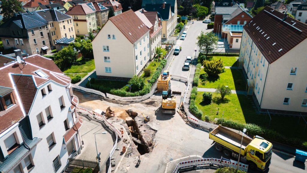 Luftaufnahme einer Baustelle im Straßenbau zur Kanalsanierung in einem Wohngebiet.