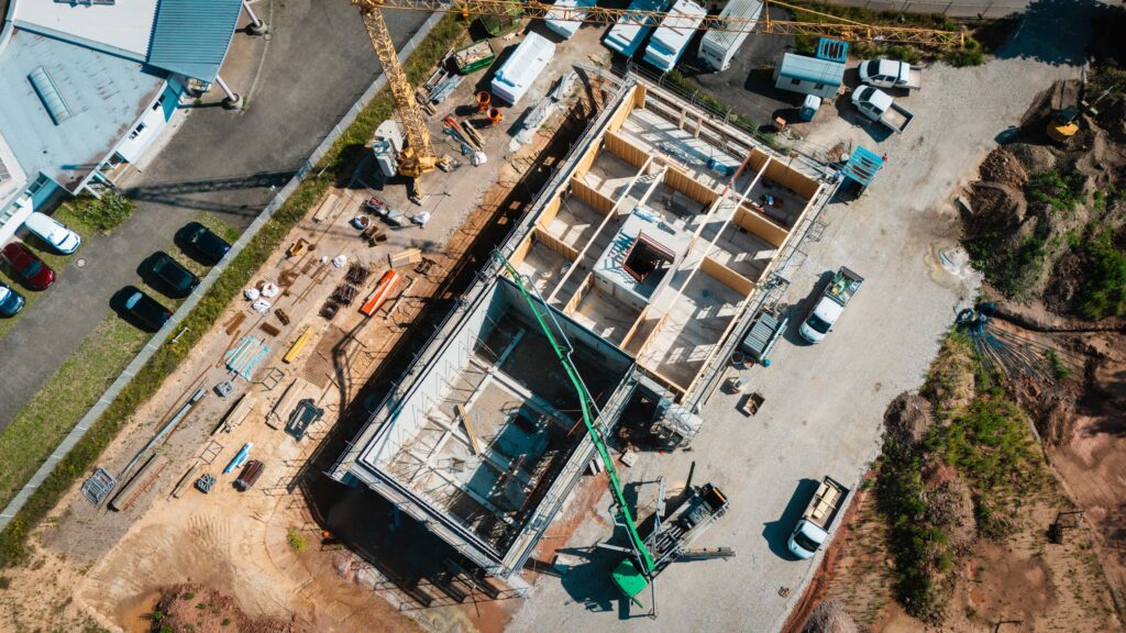 Vogelperspektive per Drohne auf gesamte Baustelle, Turmkran und Baufahrzeuge
