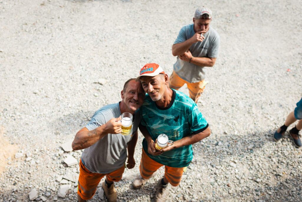 Bauarbeiter von Asphalt-Bau Chemnitz stoßen beim Richtfest fröhlich mit Biergläsern an.