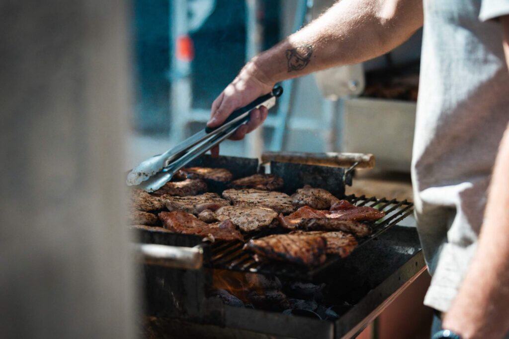 Nahaufnahme von Steaks und Grillgut auf dem Rost beim Richtfest des Gewerbegebäudes.