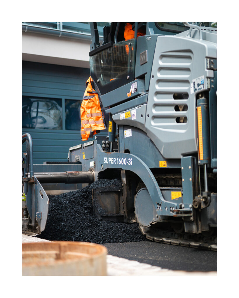Nahaufnahme der verdichtenden Bohle eines Vögele SUPER 1600-3i Asphaltfertigers während der Arbeit.
